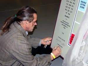 Photograph of John Kahn signing and numbering Scrabble game sculpture, December 2, 2014. Photograph courtesy of The Strong, Rochester, New York.