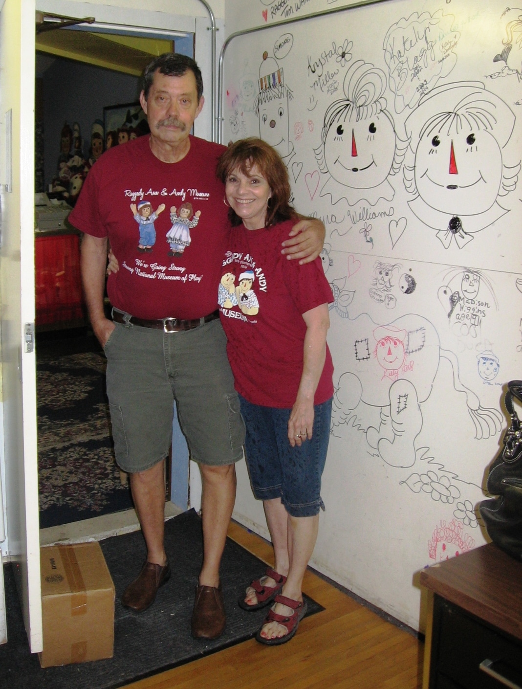 Our best friends in Arcola, Tom and Joni Wannamaker, pose by a wall of artwork inspired by Johnny Gruelle’s illustrations.