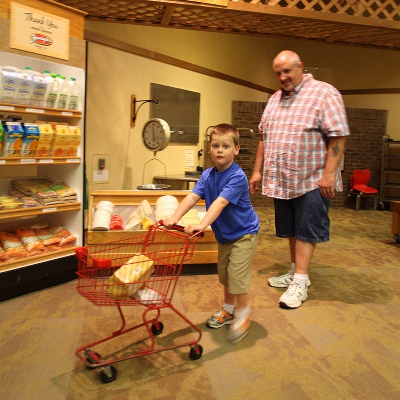 Dad and son shopping in wegmans super kids market for sensory friendly sunday