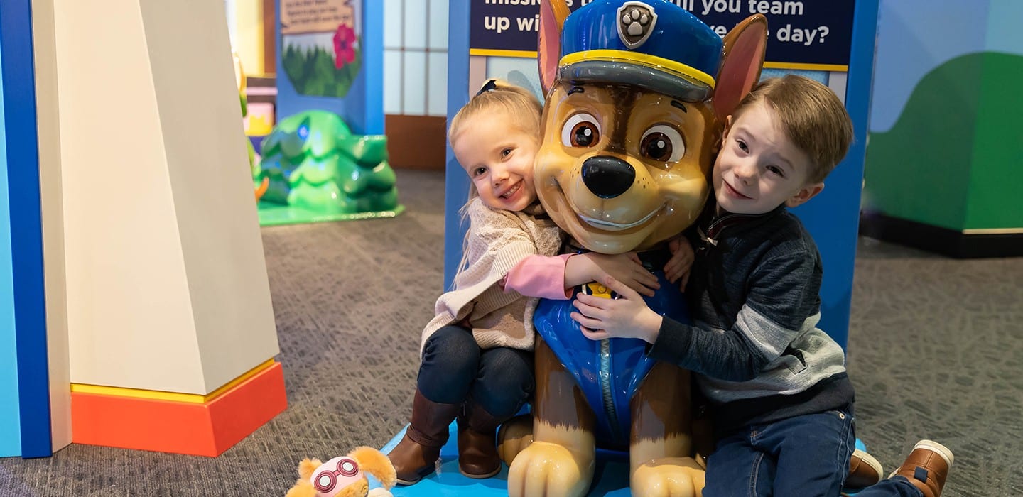 Chase character from PAW Patrol hugged by two children