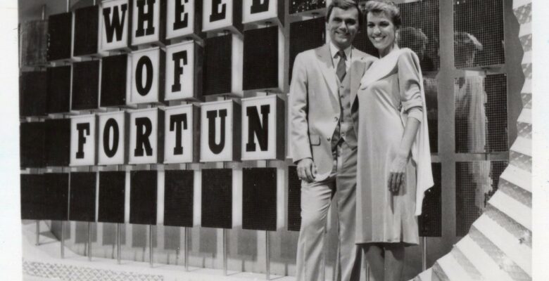 Pat Sajack and Vanna White in front of Wheel of Fortune sign