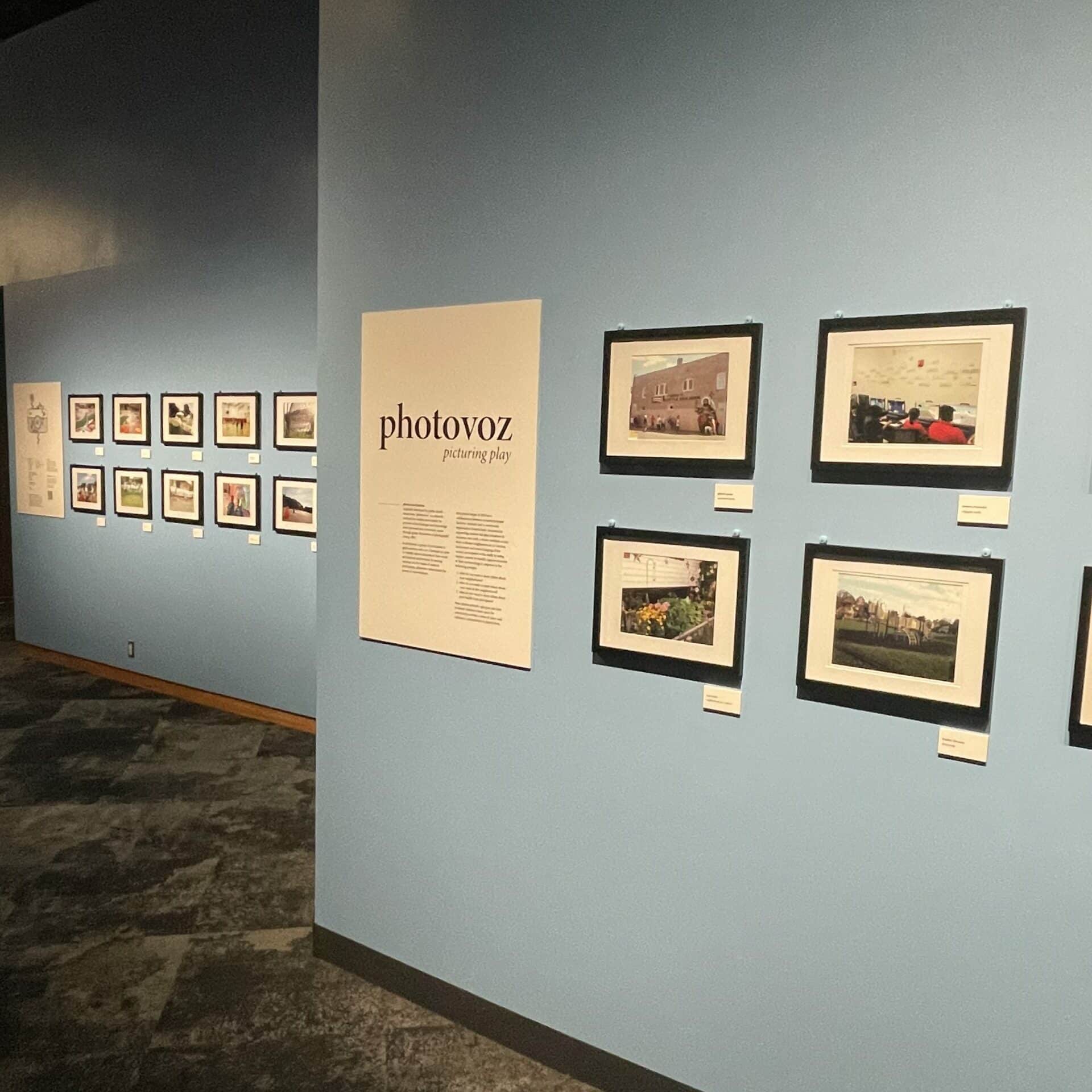 framed photos hanging on the wall with a sign that reads "photovoz: picturing play"