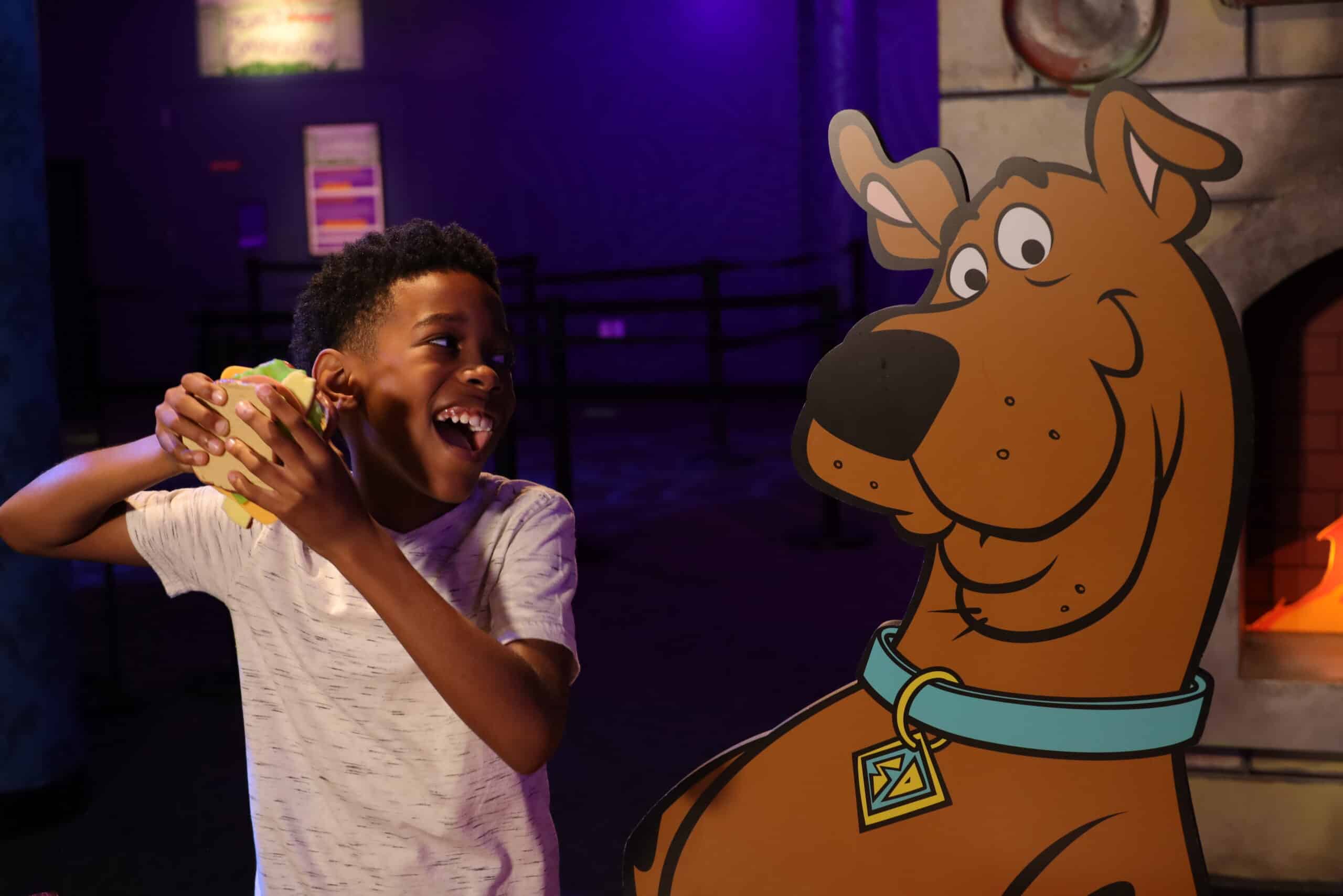 Boy feeding a sandwich to Scooby-Doo