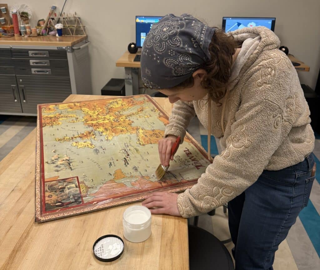 Public programs coordinator Corrina applies a layer of sealant to the reproduced board for The Game of Travel. The Strong, Rochester, New York.