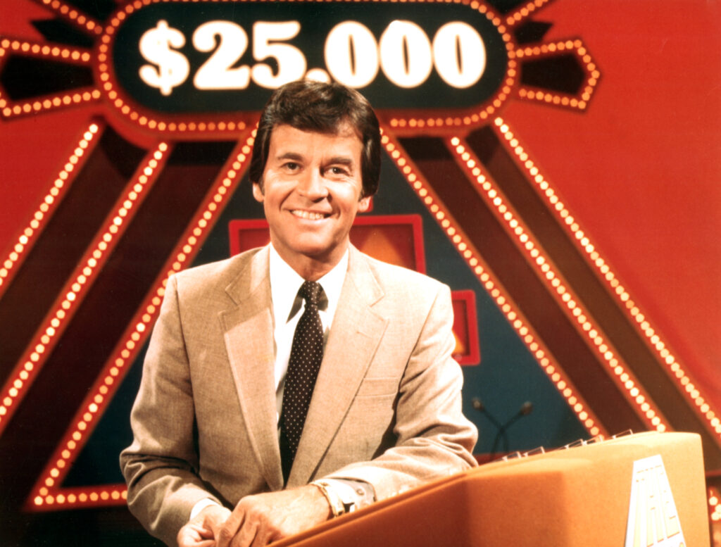 Dick Clark at podium with $25,000 sign over his head