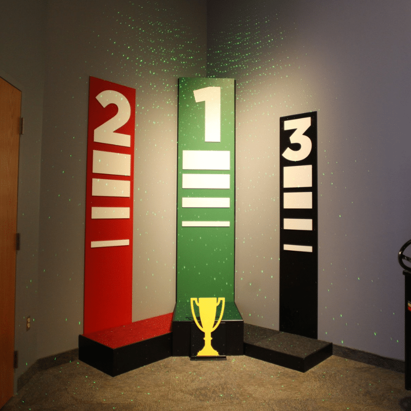 1st, 2nd, and 3rd place podiums with a trophy on the 1st place podium.