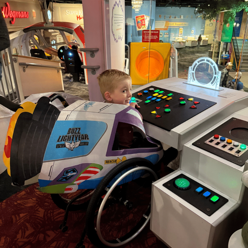 Boy wearing a Buzz Lightyear costume at the controls of the spaceship in Imagination Destination