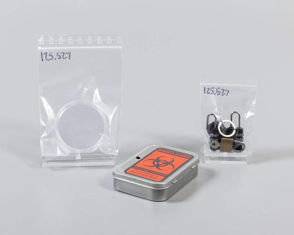 Locked tin, bag of metal pieces, and bag of plastic pieces from Escape Room in a Box: The Werewolf Experiment (First Edition), Mattel, Inc., 2016. The Strong National Museum of Play, Rochester, New York.